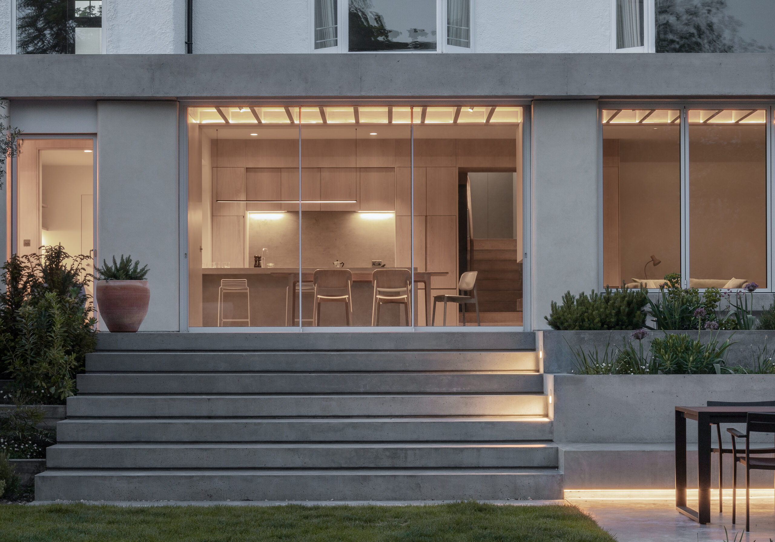 View from garden into kitchen. Bespoke concrete steps lead up to glazed doors.