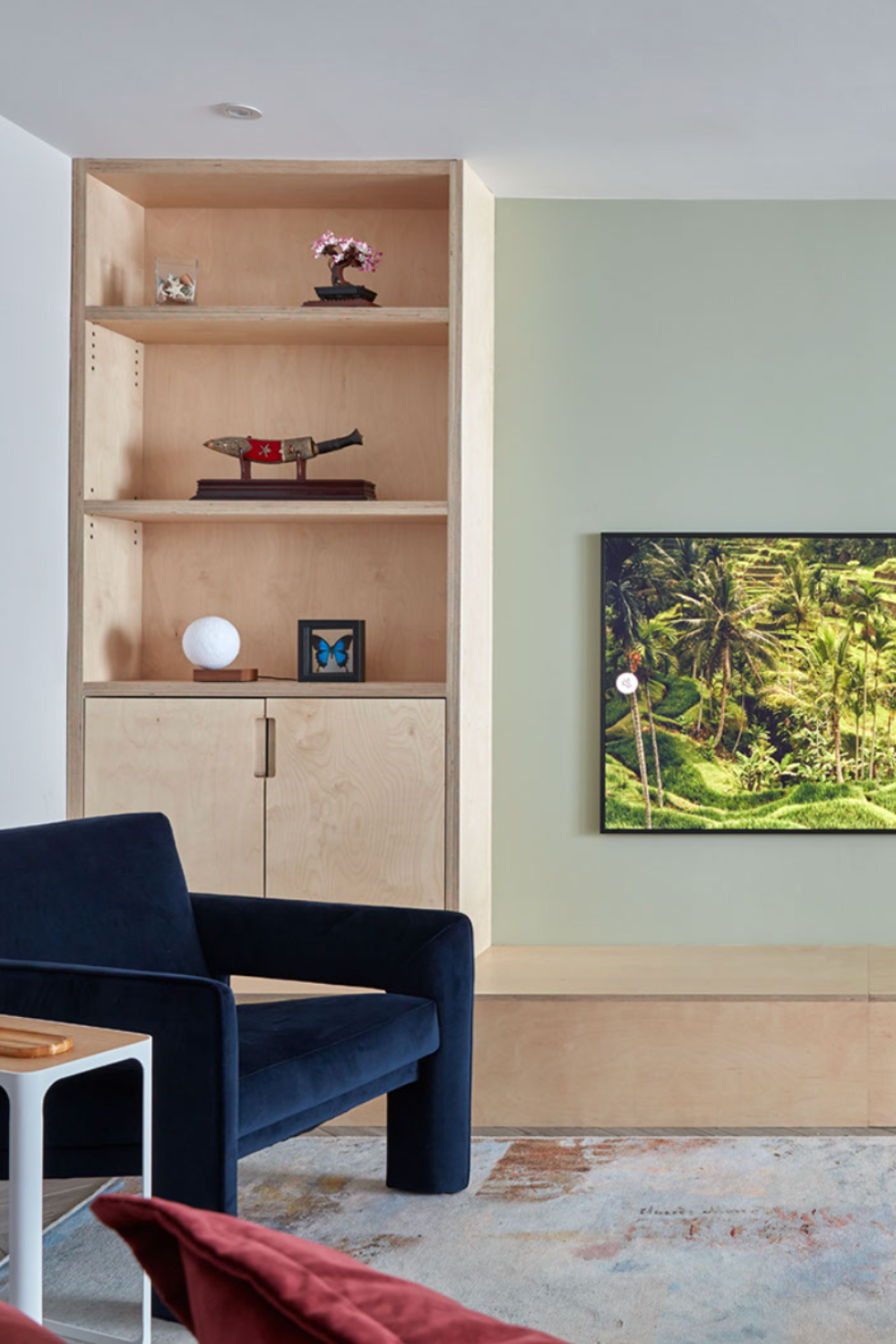 Lounge room with built in bespoke cabinetry . Blue chair in velvet fabric. TV shown on wall