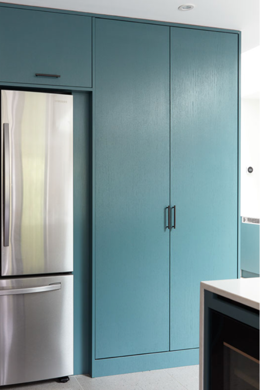 Tall kitchen cabinets shown closed next to built in fridge freezer